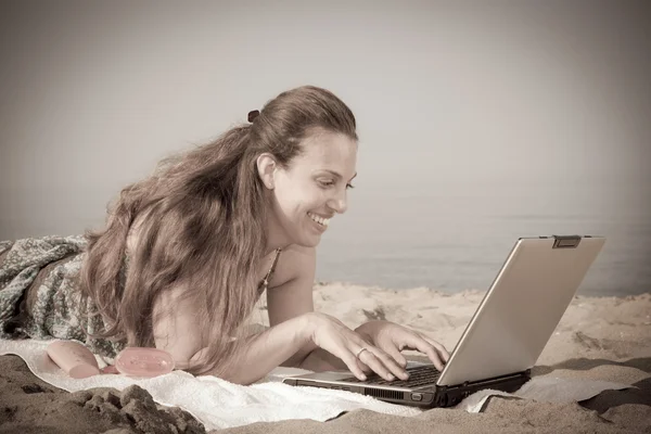 Kvinna som arbetar vid dator på stranden — Stockfoto