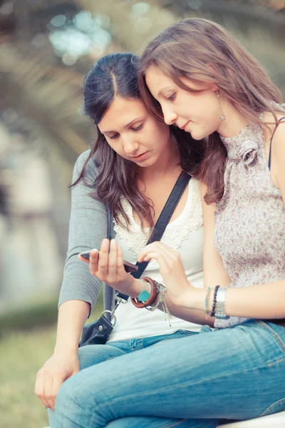 Две красивые женщины отправляют сообщения с мобильного телефона — стоковое фото
