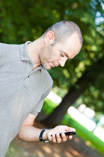 Человек с мобильным телефоном в парке — стоковое фото