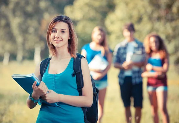 Jonge vrouwelijke student in het park met andere vrienden — Stockfoto