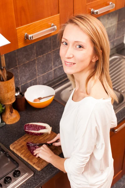 Jeune femme dans la cuisine coupant des légumes — Photo