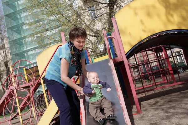 Mother holding son on slide — Stock Photo, Image
