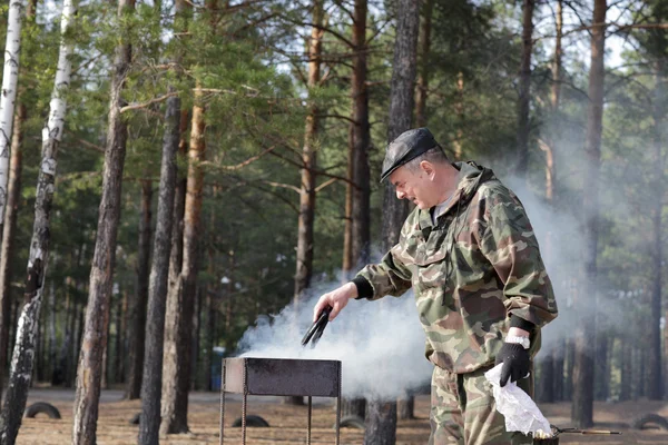 Uomo che mette carbone nel barbecue — Foto Stock