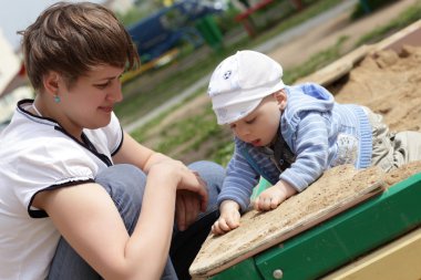 sandbox içinde onun yürümeye başlayan çocuk ile anne