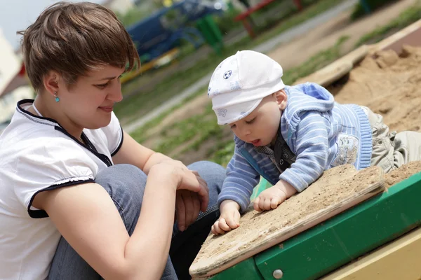 Mãe com sua criança na caixa de areia — Fotografia de Stock