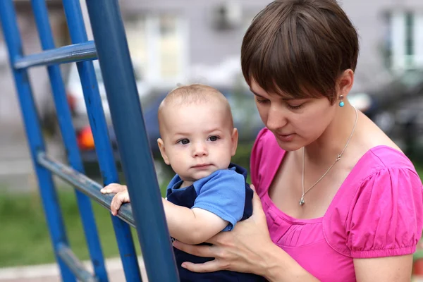 Mother holding baby on ladder — Stock Photo, Image