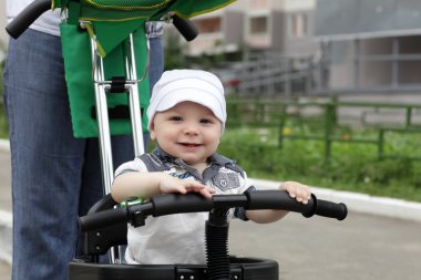 Child on tricycle with push handle clipart