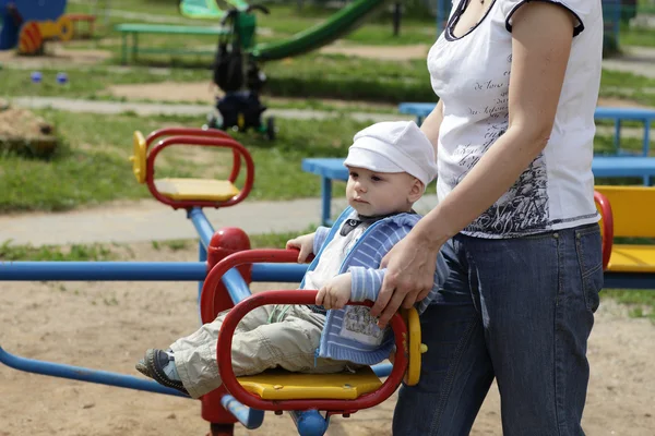Mother pushing carousel with child — Stock Photo, Image