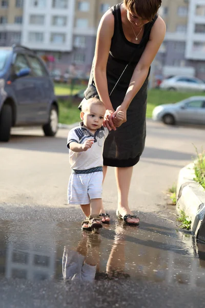 Dziecko z matką, chodzenie po kałuży — Zdjęcie stockowe