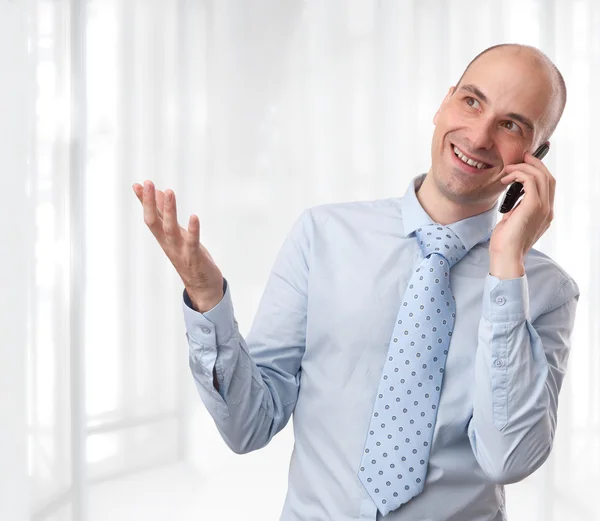 Бизнесмен улыбается и разговаривает по телефону в офисе — стоковое фото
