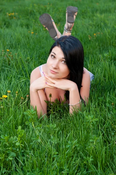 Brunett flicka liggande på gräs. — Stockfoto