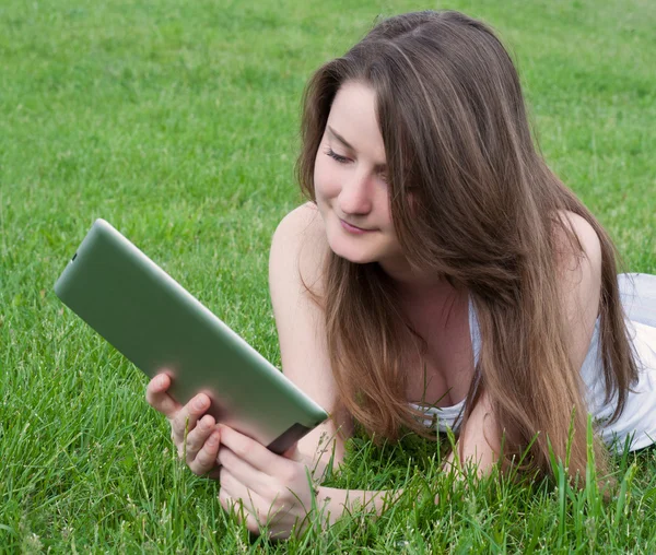 Vrouw liggen op gras met de Tablet PC. — Stockfoto