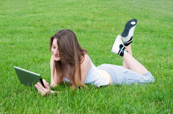 Lucky girl couché sur l'herbe avec tablette . — Photo