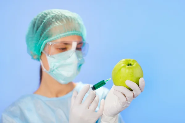 年轻的女医生注射绿色苹果与注射器的蓝 — 图库照片