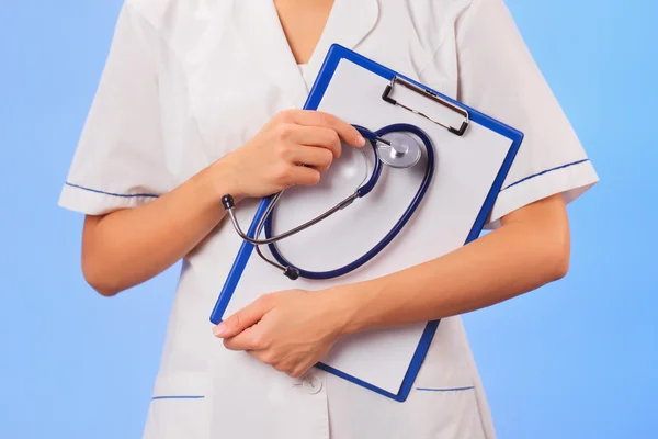 Doctor with copyspaced clipboard waist-high portrait on blue — Stock Photo, Image