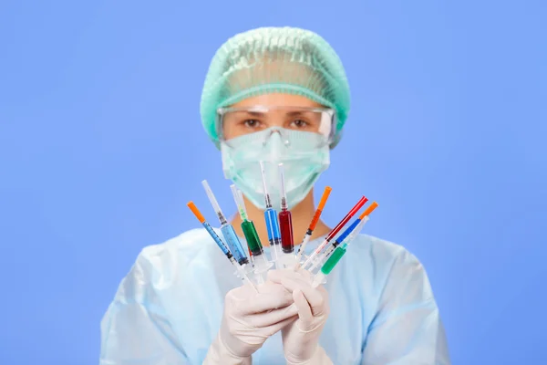 stock image Young woman doctor with many multicolor syringes in hands on blu