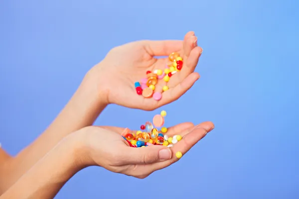 Pills, tablets and drugs pouring in doctor's hands on blue backg — Stock Photo, Image