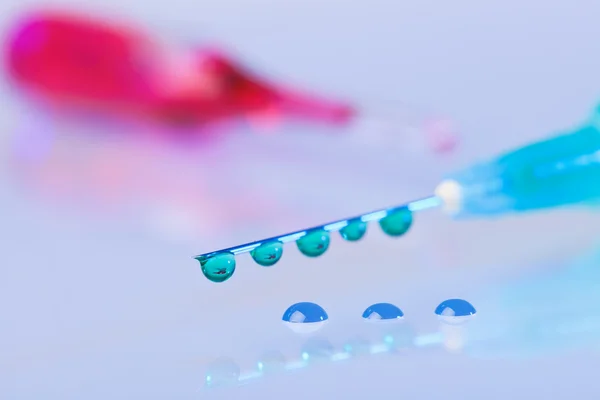 Spritzennadel mit grünen Flüssigkeitstropfen auf Wassertropfen — Stockfoto