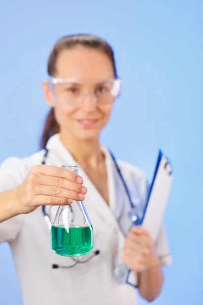 Young woman therapeutic doctor showing medical retort with green — Stock Photo, Image