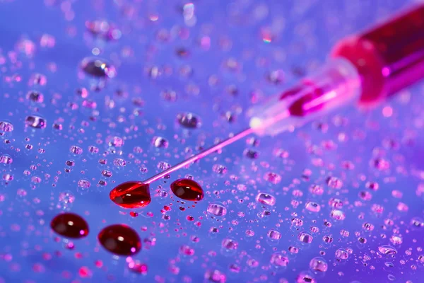 Folyadék (vér) injekciós tű csepp cseppek víz háttérben — Stock Fotó