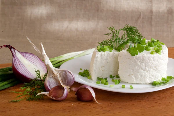 Коттедж с зеленью и луком на тарелке — стоковое фото