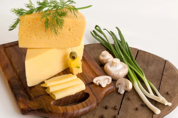 Käse mit Gemüse und Pilzen auf einem Holzbrett — Stockfoto
