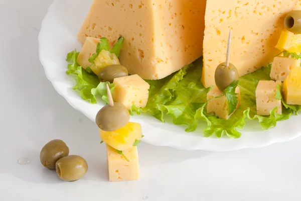 Sýr se zelení a olivami na talíři — Stock fotografie