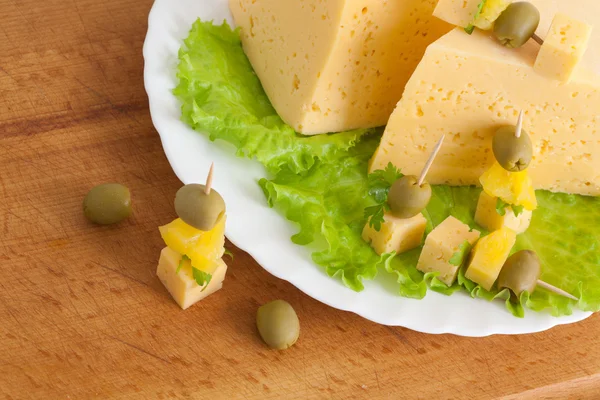 Kaas met Groenen en olijven op een houten bord — Stockfoto
