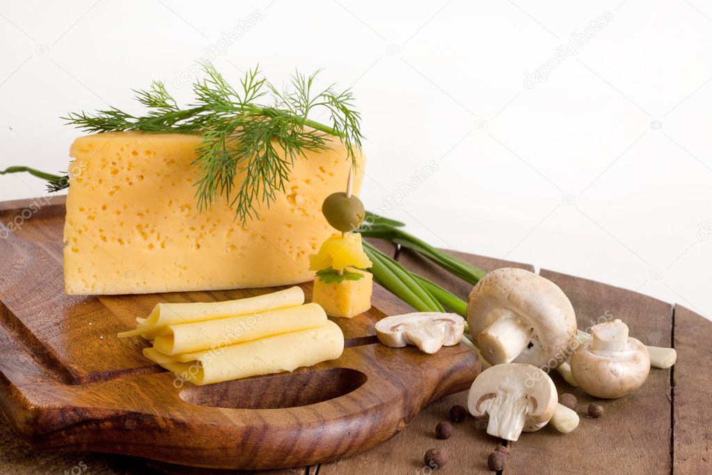 Cheese with greens and mushrooms on a wood board