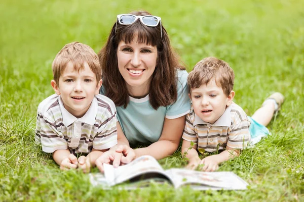 Мать и сыновья читают книгу на открытом воздухе — стоковое фото