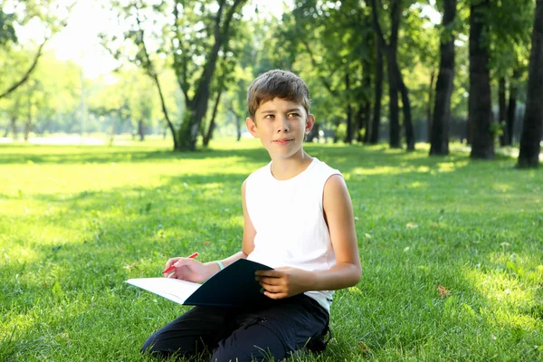 Retrato de um menino com um livro no parque — Fotografia de Stock