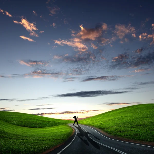 Homem caminhando ao amanhecer ao longo da estrada — Fotografia de Stock