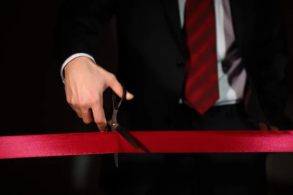 stock image Businessman with scissors cuting a red ribbon