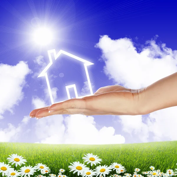 House and human hand against blue sky Stock Image