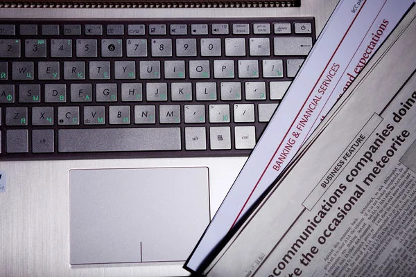 Notebook keyboard with a newspaper — Stock Photo, Image