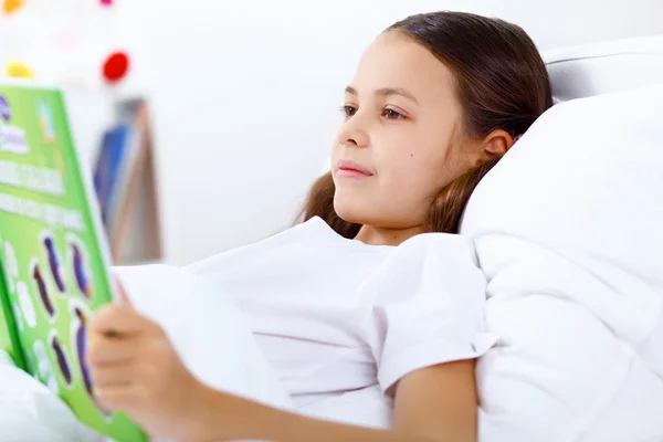 Meisje met een boek in bed thuis — Stockfoto
