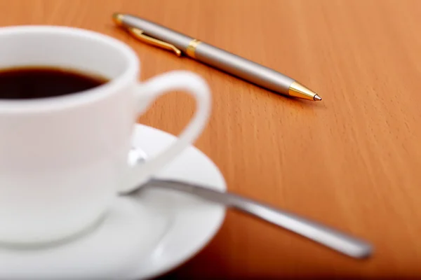 Svart kaffe i en kopp och penna — Stockfoto