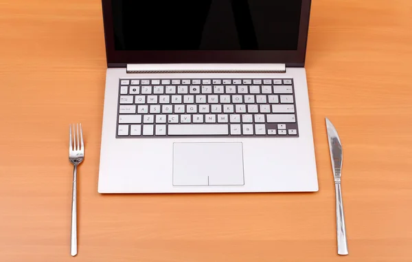 Ноутбук с вилкой и ножом — стоковое фото