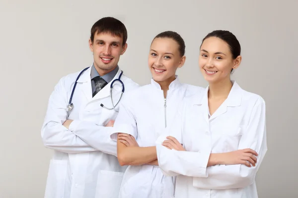Tre giovani medici in uniforme bianca — Foto Stock