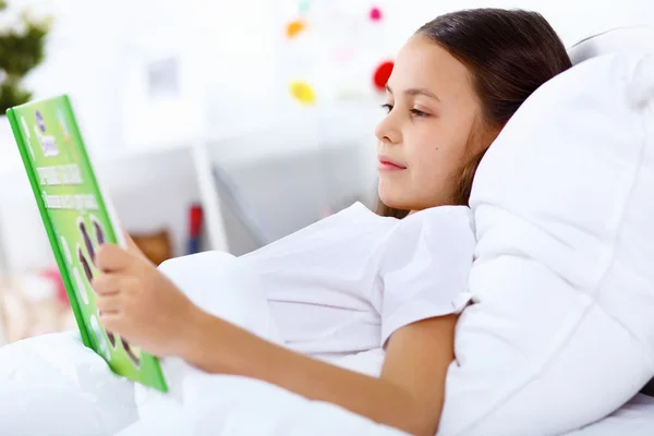 Menina com um livro na cama em casa — Fotografia de Stock
