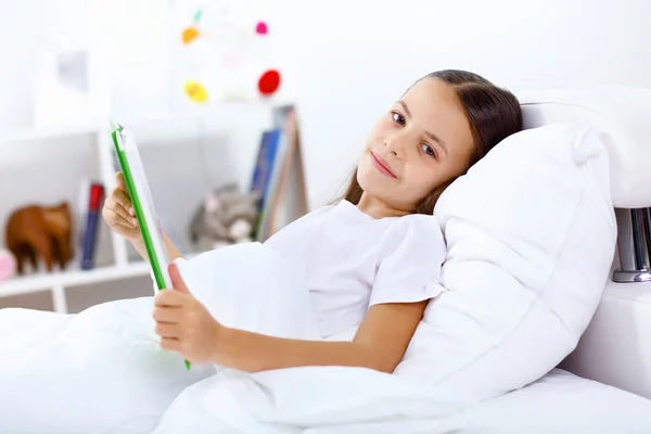 Menina com um livro na cama em casa — Fotografia de Stock