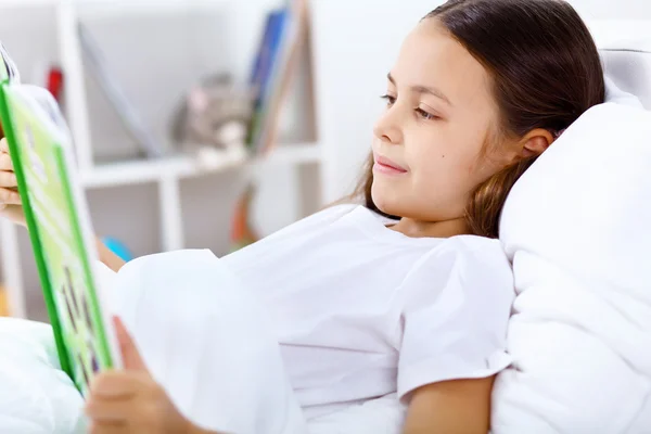 Dívka s knihou v posteli doma — Stockfoto