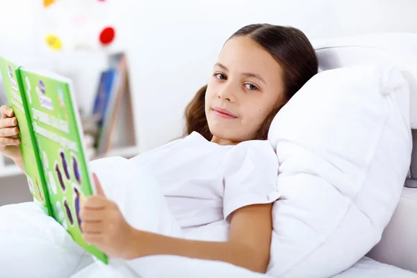 Κορίτσι με ένα βιβλίο στο κρεβάτι στο σπίτι — Φωτογραφία Αρχείου
