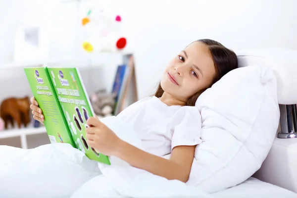 Meisje met een boek in bed thuis — Stockfoto