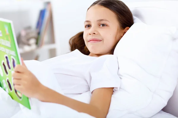 Stock image Girl with a book in bed at home