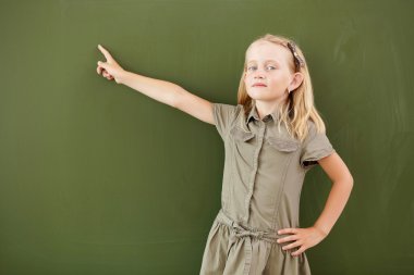 Scoolgirl standing near blackboard clipart