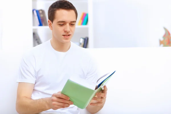 Mladý muž doma s knihou — Stock fotografie