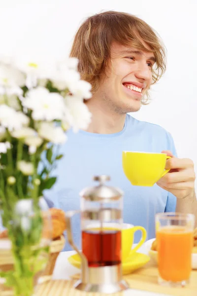 Молодой счастливый человек пьет чай — стоковое фото
