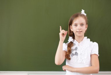 Scoolgirl standing near blackboard clipart