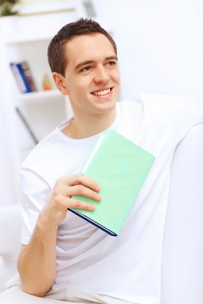 Młody człowiek w domu z książką — Zdjęcie stockowe